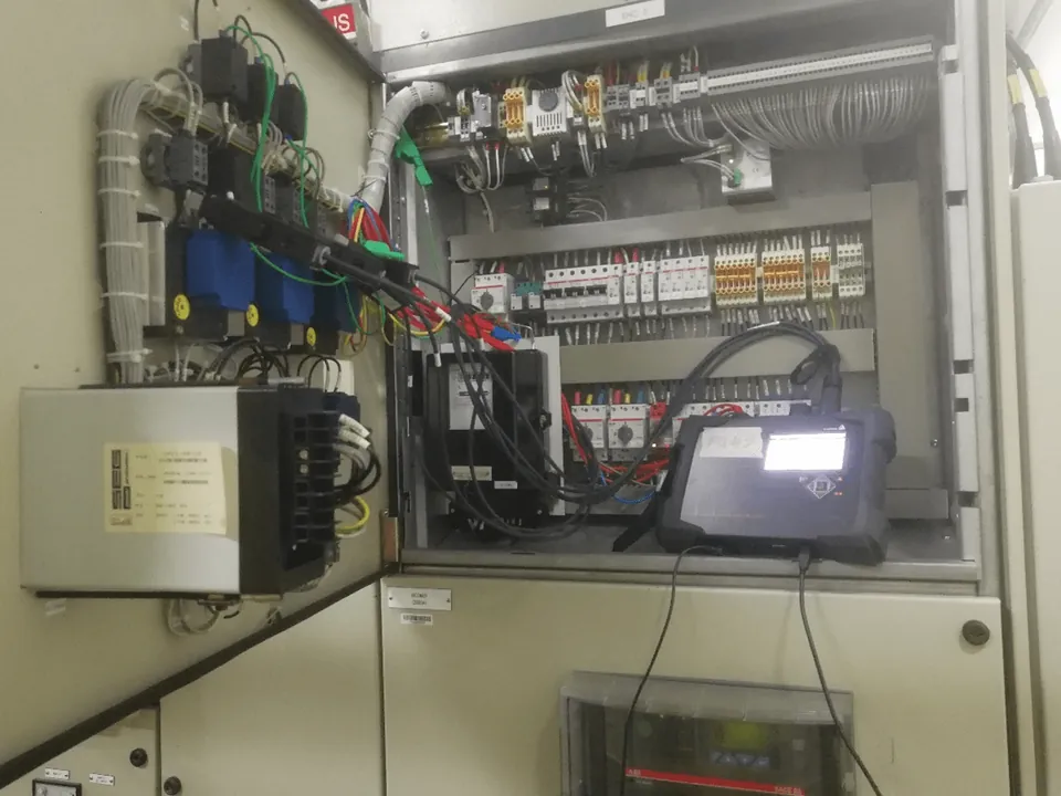 A power quality analyser connected inside an open electrical panel during an audit